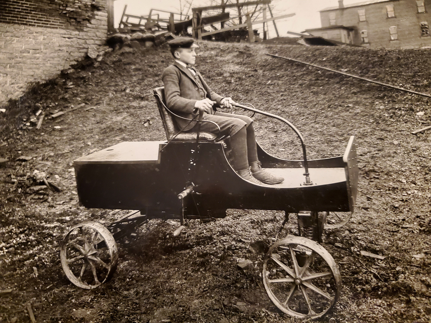 Teenage boy wearing suit sitting on 1-cylinder automobile 