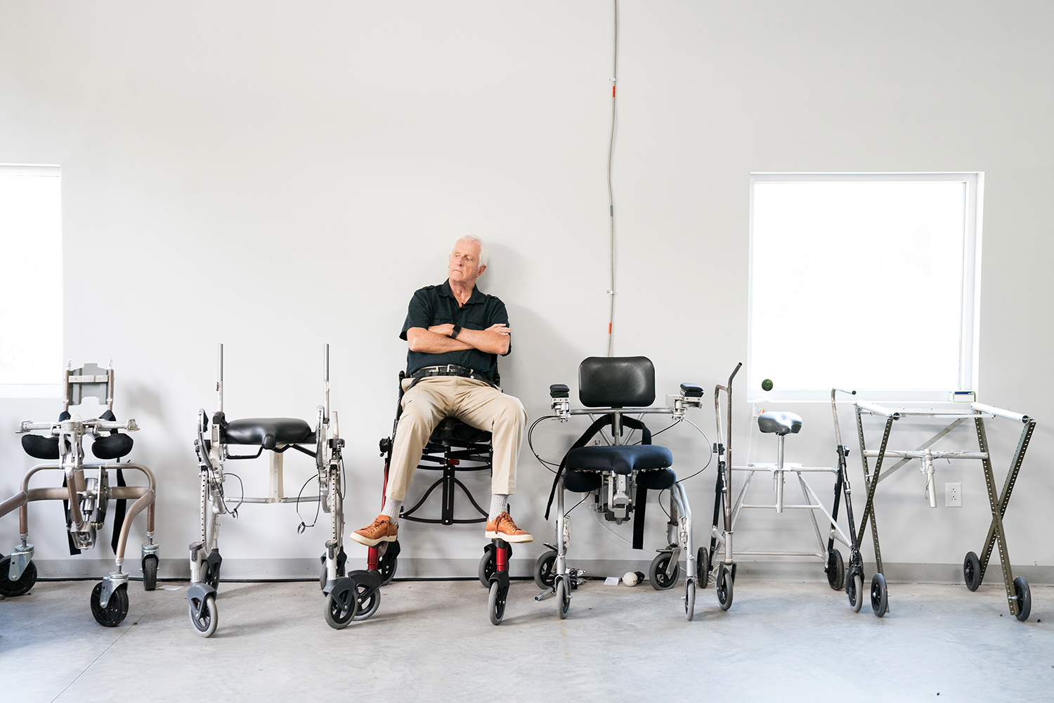 garrett brown sitting in middle of evolution of six chairs in white studio