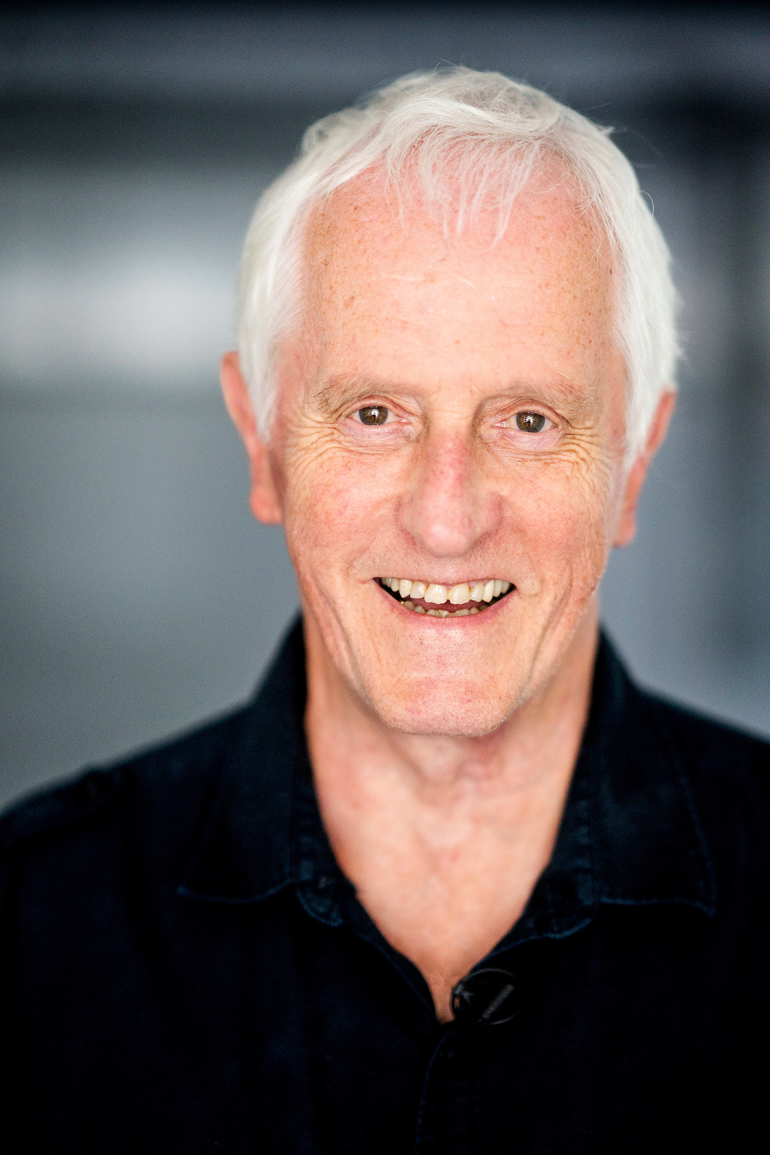 headshot garrett brown in black shirt blue background smiling