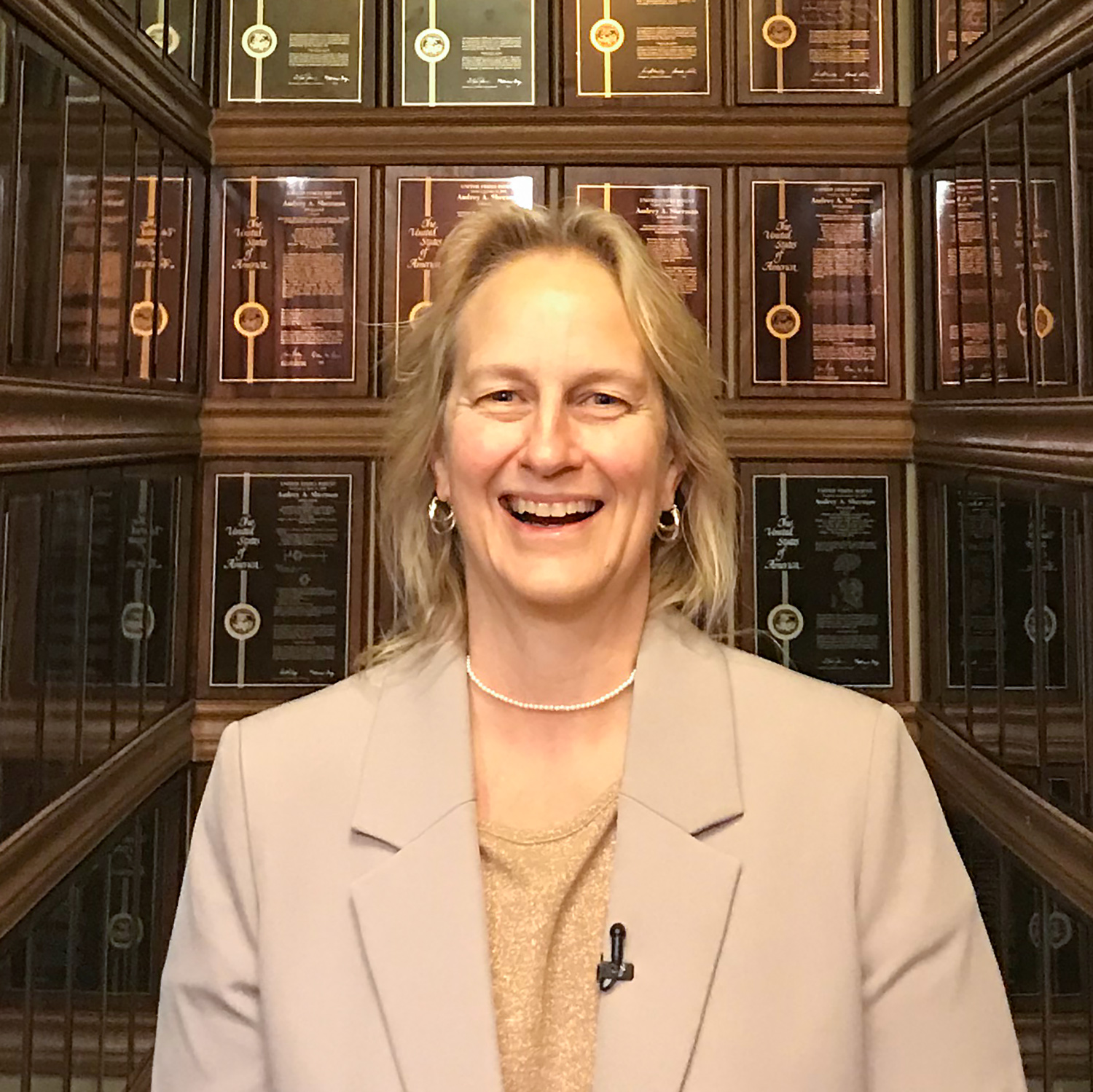 Audrey Sherman poses in her stairwell with the plaques 3M awarded her for her patents.