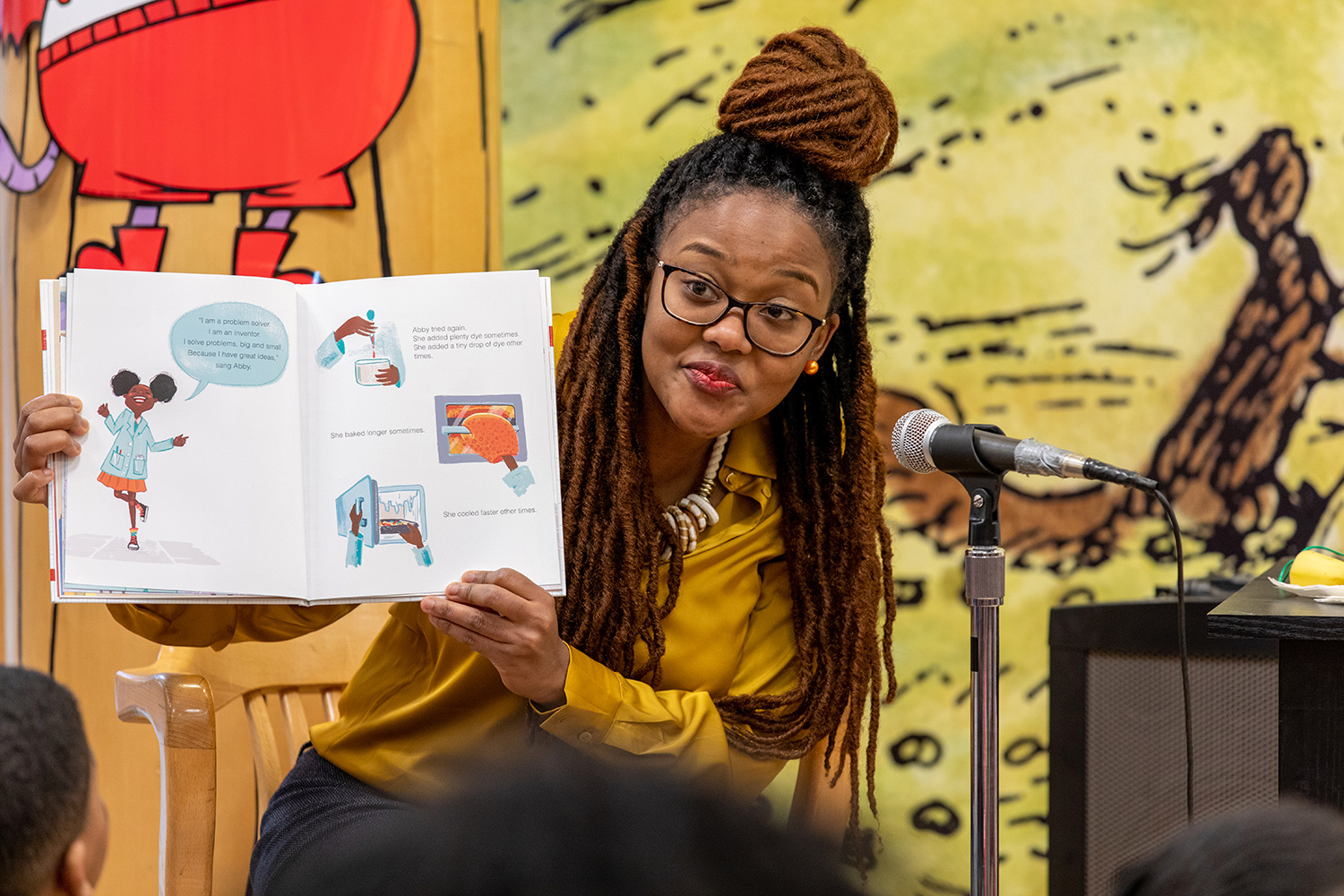 Arlyne Simon holds her open book in front of a group of children.