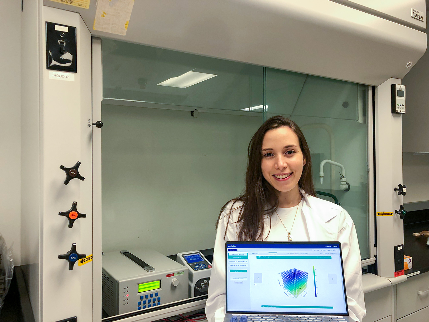 Standing in the lab, Daniela Blanco holds up a laptop that shows the Sunthetics software running on the computer screen.