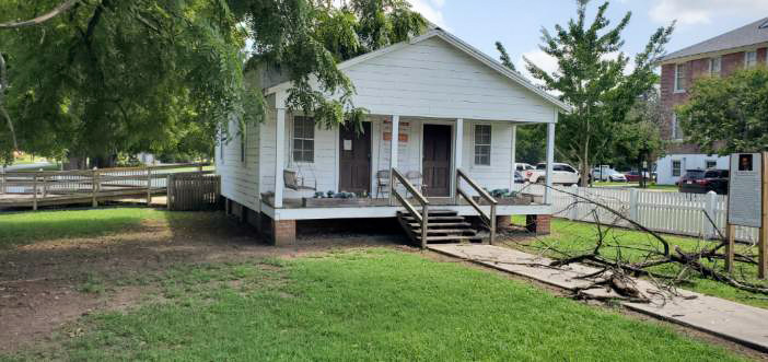 White single story home with a front porch, staircase, and walking path.