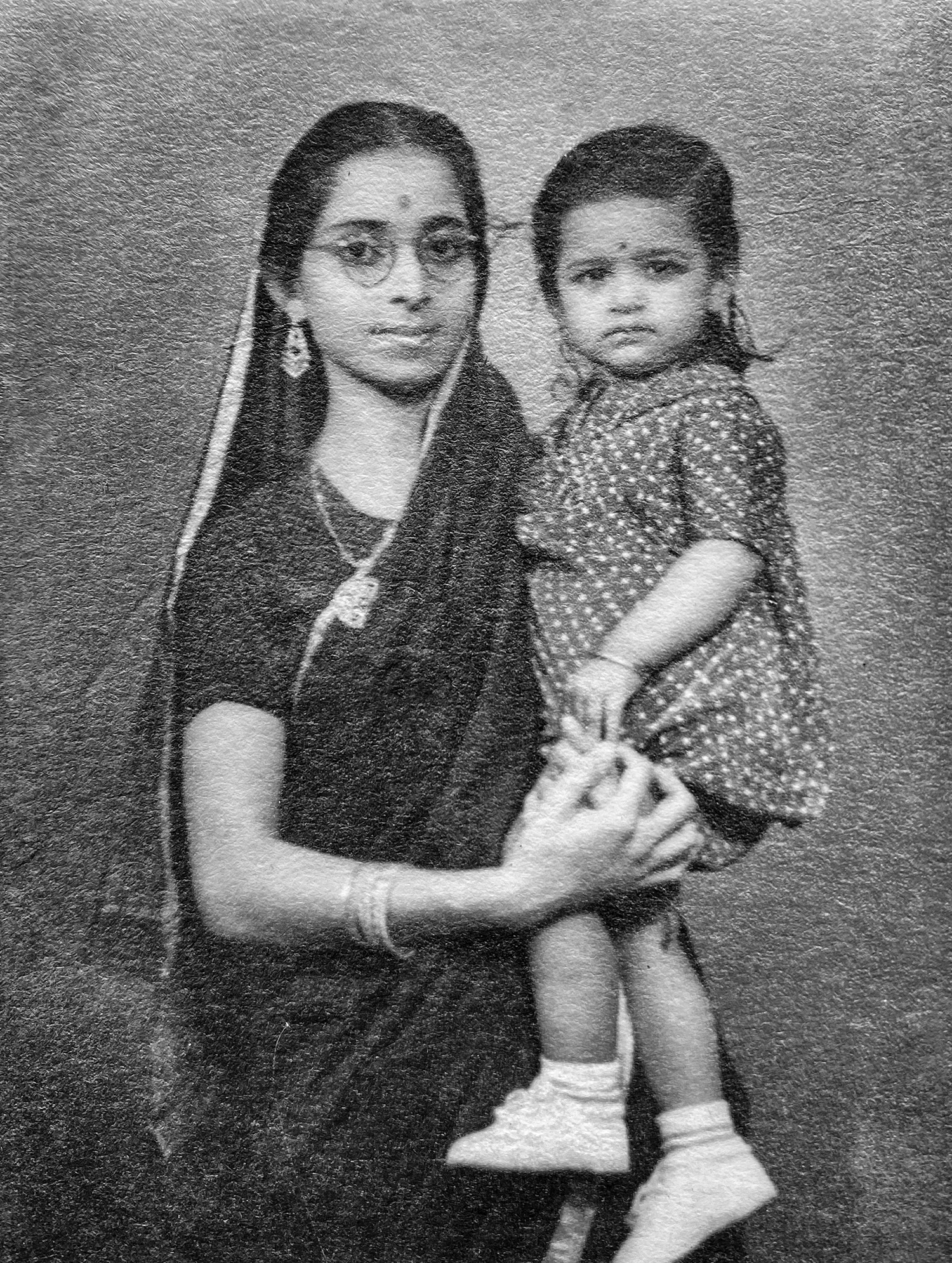 Woman wearing traditional Indian clothing holding a small child in her arms