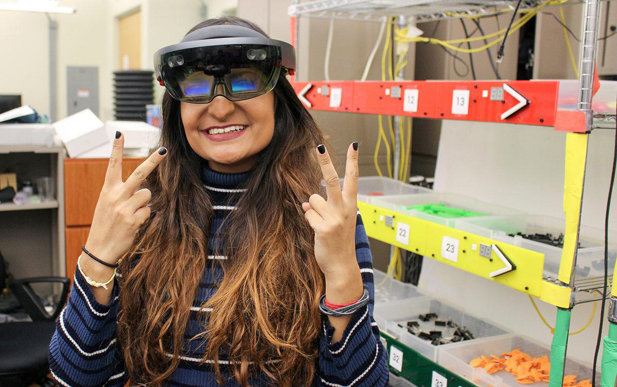 Woman wearing smart glasses poses peace signs with her hands.