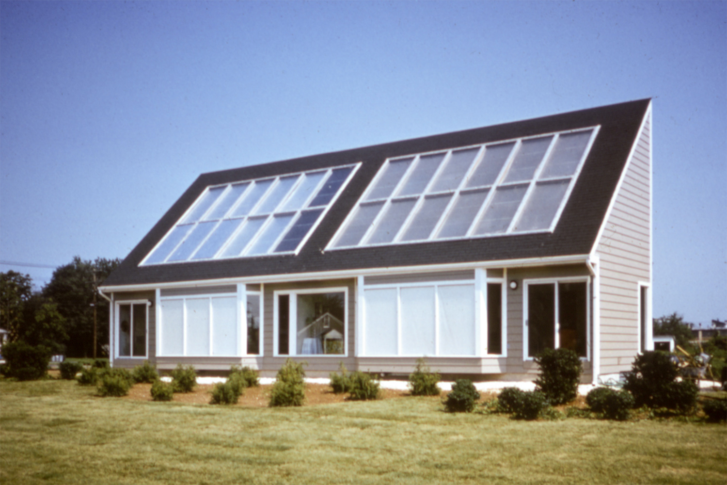 A wooden house with glass panels covering a slanting roof.