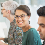 A group of people working at separate computers and one person looking up and smiling 