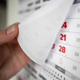 A hand flipping the page of a calendar book. 