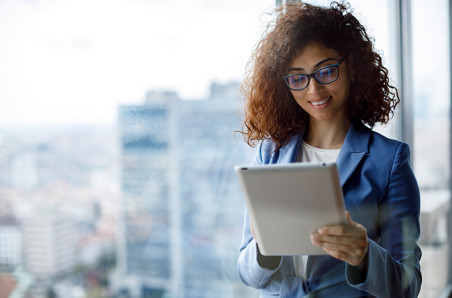 Woman with glasses smiling and looking at an electronic tablet