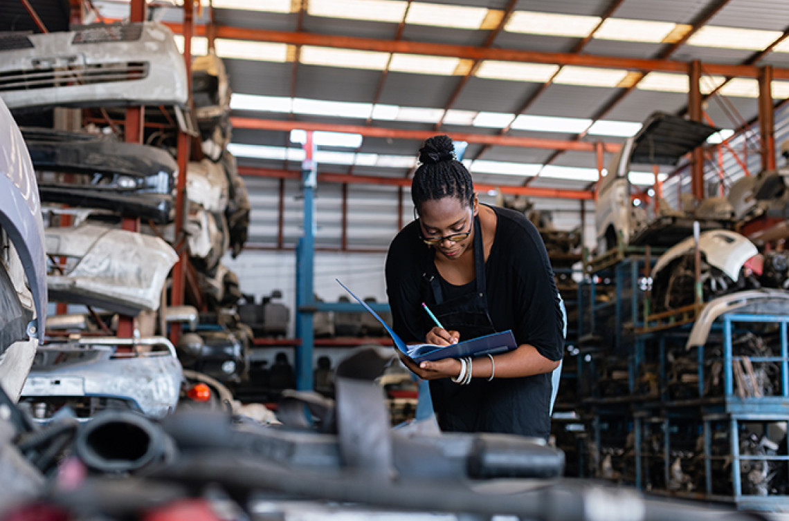 Technical worker in an automotive industry setting takes notes in her binder