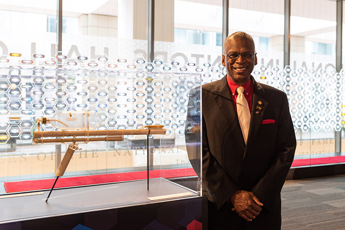 Lonnie Johnson poses next to a blueprint model of the super soaker