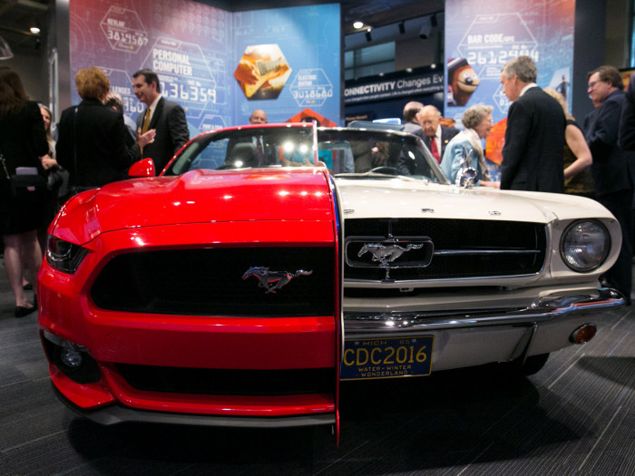 NIHF Museum exhibit featuring two halves of a Ford Mustang, a white half from 1965 and a red half fr