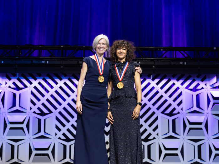 Two White female inventors in formal dresses stand on stage with their National Inventors Hall of Fa