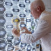 Inventor Robert G. Bryant in a white blazer places his name plate on a hexagon shape  plaque as part