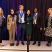 Undergraduate students, two women and two men, stand on stage with USPTO Director Kathi Vidal and Na