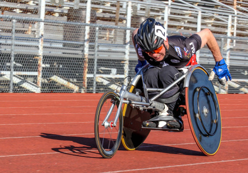 Rory Cooper  in leaned back in a racing chair on a red track, leaned down to become aerodynamic, pushing himself to win