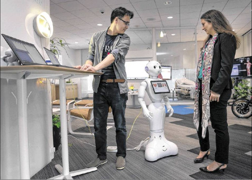 Susann Keohane and co-worker at the IBM aging in place environment/lab with the friendly looking Multi-Purpose Eldercare Robot Assistant (IBM MERA), a first of a kind Watson-enabled application designed to aid the elderly and assist caregivers with real-time information about their health.