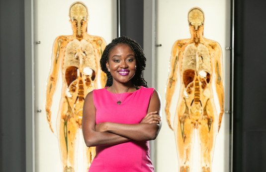 Arlyne Simon stands in front of two body scan images.