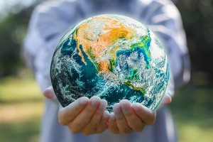 Person holding a globe in their hands, standing outside