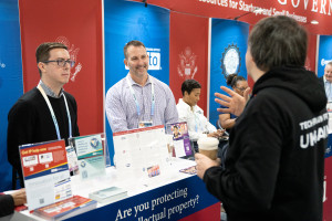 Three people chatting at the USPTO booth at the Consumer Electronics Show (CES).