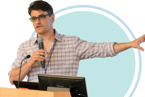 A man standing behind a podium and holding a microphone while giving a presentation.