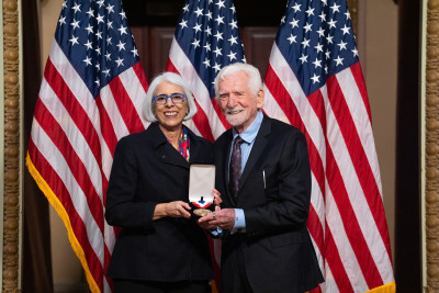 Martin Cooper and White House Office of Science and Technology Policy Director Arati Prabhakar smile and show a medal.