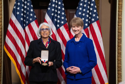 Kristina M. Johnson and White House Office of Science and Technology Policy Director Arati Prabhakar smile and show a medal.