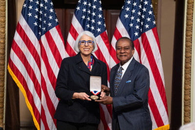 Victor B. Lawrence and White House Office of Science and Technology Policy Director Arati Prabhakar smile and show a medal.