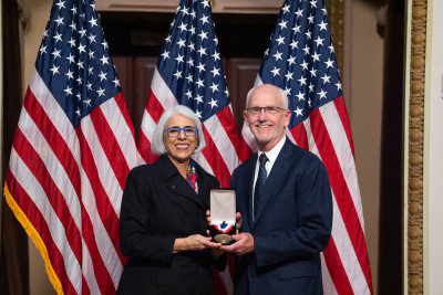 Paul G. Yock and White House Office of Science and Technology Policy Director Arati Prabhakar smile and show a medal.