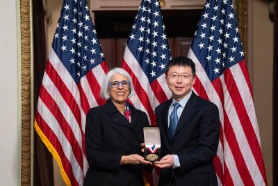  Feng Zhang and White House Office of Science and Technology Policy Director Arati Prabhakar smile and show a medal.