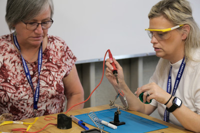 Two educators at NSTI 2024 using a soldering tool during the Invention Challenge. 