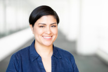 Julianne T. in a navy blue collared with dark eyes and short dark hair smiles.