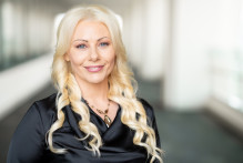 Headshot of USPTO Public Affairs Specialist Christy W. She has blonde hair and wears a blacks satin blouse with a beaded stone necklace.