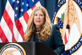 Kathi Vidal speaking at a podium in front of the flags.