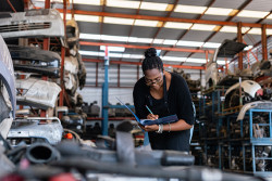 Technical worker in an automotive industry setting takes notes in her binder