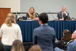 Two audience members stand and speak to Kathi Vidal and Dave Gooder