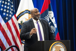 Acting Director Derrick Brent speaks from a USPTO podium at the agency's headquarters in Alexandria, Virginia, on January 15, 2025. In the background behind Brent are flags, including those of the United States and the USPTO.