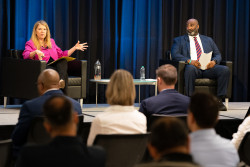 USPTO Director Kathi Vidal (on the left) and Deputy Director Derrick Brent (on the right) are seated next to each other on July 18 at an agencywide town hall. They both face the audience, and Vidal is speaking and gesturing. The event was held in the Clara Barton Auditorium on the headquarters campus in Alexandria, Virginia. 