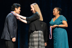 Acting Director of the USPTO Coke Stewart places a medal around the neck of inductee David Huang.