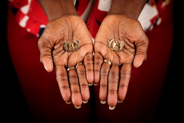 hands holding “Eagle Rising” insignia