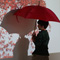 Photo of a young boy holding a red umbrella standing in front of a projector displaying little red umbrellas raining down.