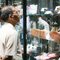 Photo of a man looking in a glass case displaying the bottom soles of a pair of boots.