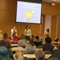 Photo of children sitting in a conference room listening to a speaker.